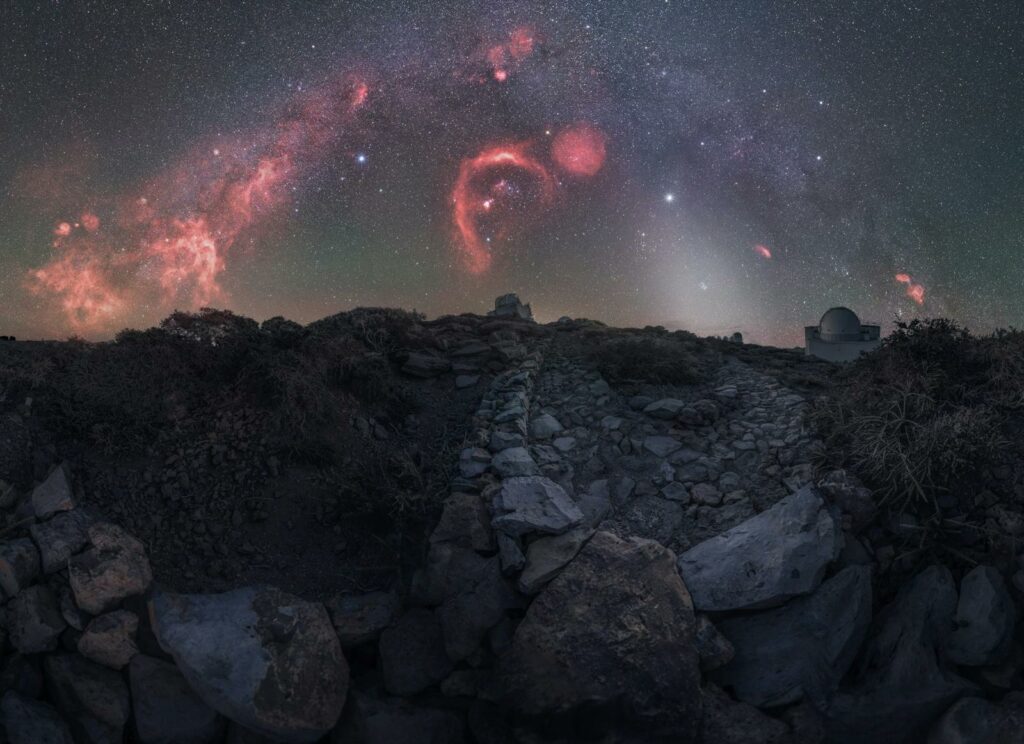 Breathtaking view of the Milky Way and celestial formations over rugged terrain.